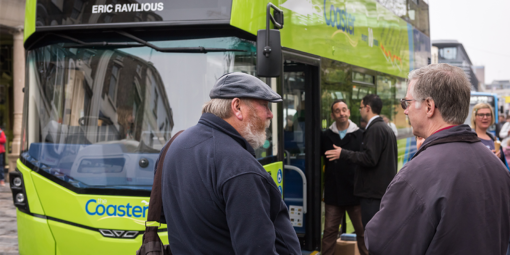 Passengers talking to each other with a Coaster bus in front of them
