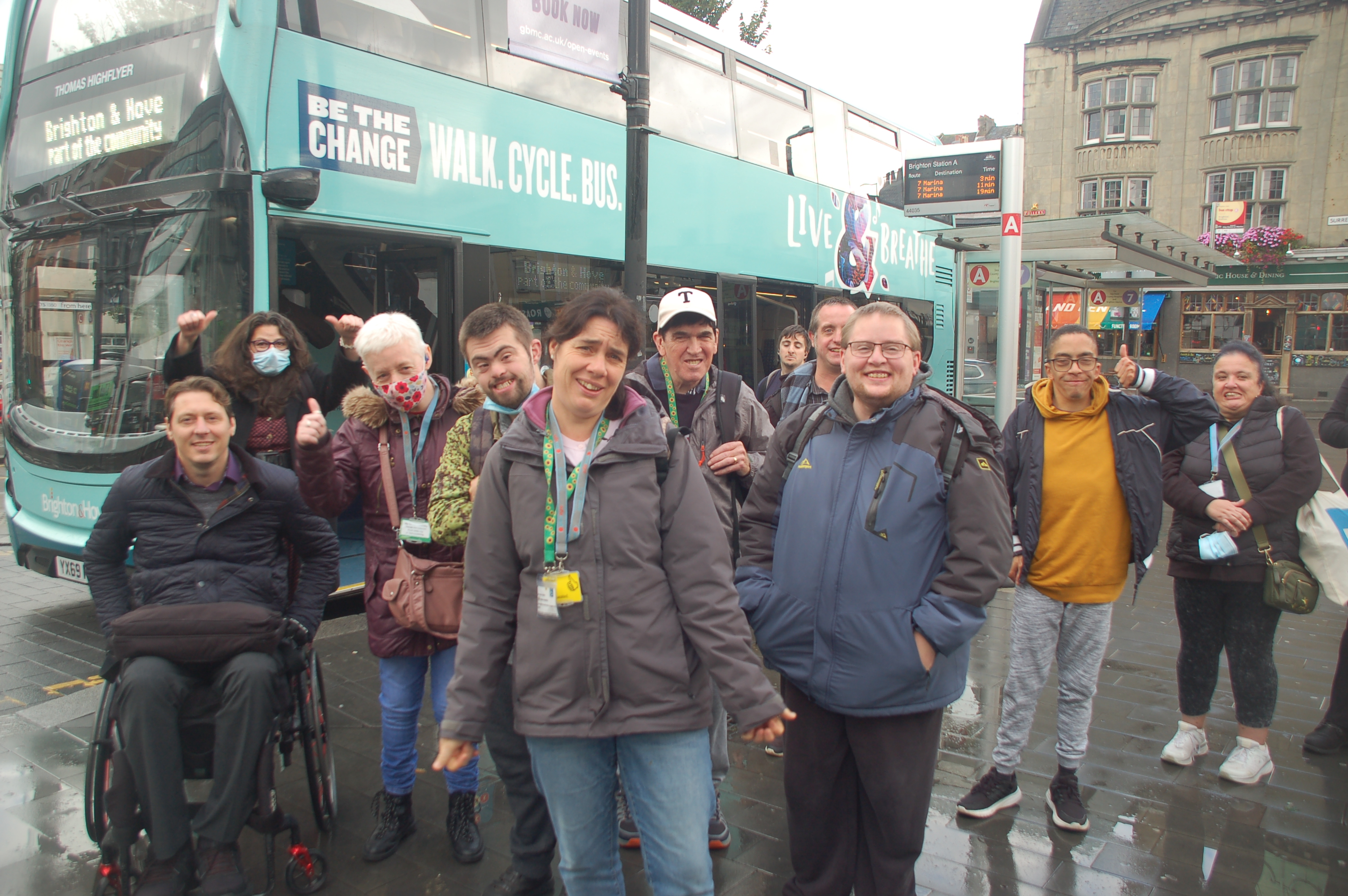 Staff and attendees pose in front of a bus