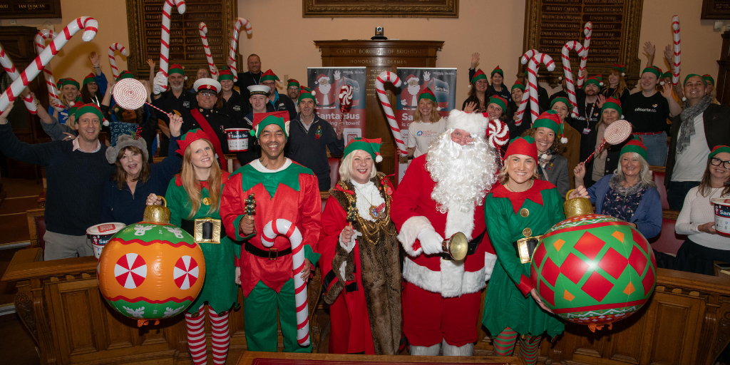 photo of the mayor and santa, with an elf either side and charity representatives waving candy canes behind
