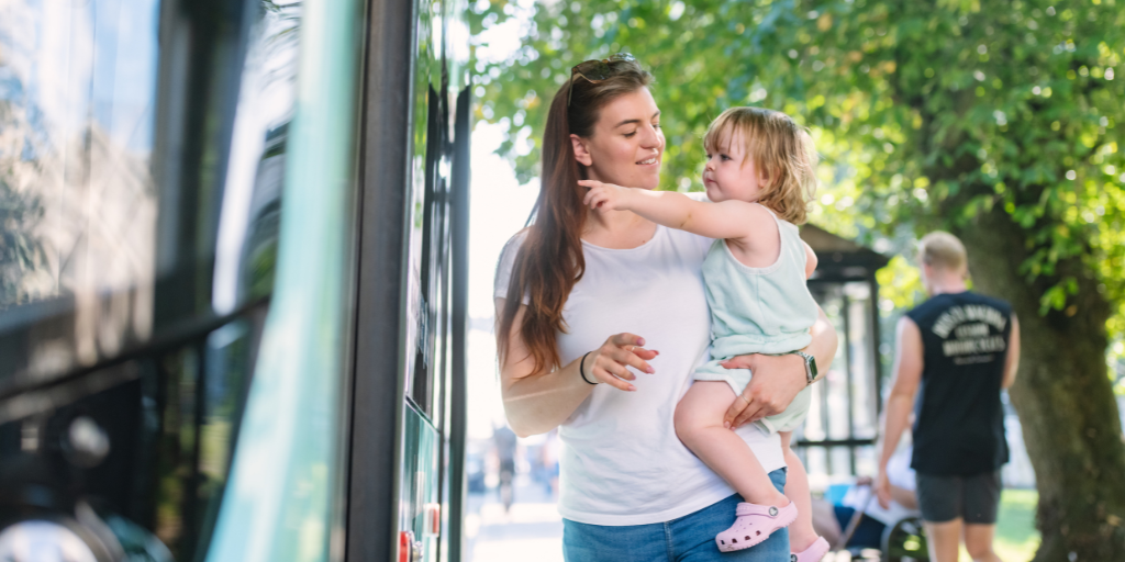 women holding a toddler about to board a bus